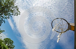 A broken basketball net dangles from a hoop attached to a metal backboard.