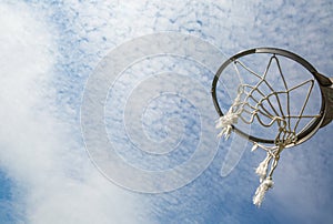 A broken basketball net dangles from a hoop attached to a metal backboard. photo