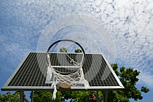 A broken basketball net dangles from a hoop attached to a metal backboard. photo