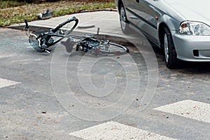 Broken bicycle and car on the road after dangerous collision