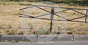 Broken black metal fence on a lawn with mown grass