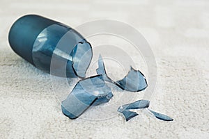 Broken blue glass vase on carpet, closeup