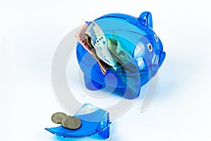 A broken blue piggy bank from a virus crisis. Money-saving plan failure signal. isolated background money and piggy bank close-up