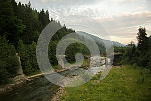 Broken bridge over the river among the mountains and forest