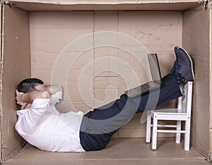 Broken businessman in a cardboard office, stress and depression from overwork