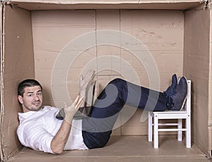 Broken businessman in a cardboard office, stress and depression from overwork