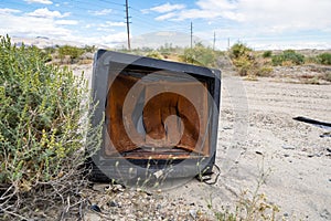 A broken, busted old CRT TV set sits abandoned and rotting in the desert of California