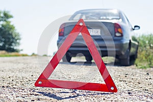 Broken car concept, breakdown triangle on road. Sign of emergency stop car on the road. Broken down car dangerously parked awaitin