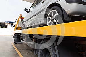 Broken car on flatbed tow truck being transported for repair