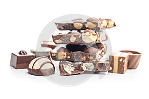 Broken chocolate bars with nuts and pralines isolated on white background