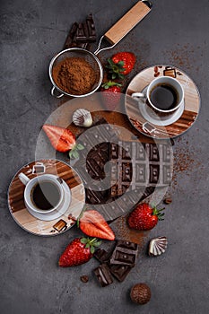 Broken chocolate blocks with strawberries and 2 cups of coffee o