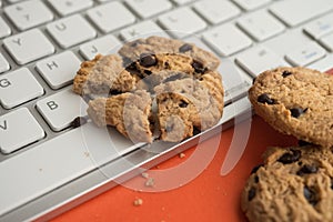 Broken chocolate chip cookies on keyboard computer background.