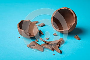 Broken chocolate egg on light blue background
