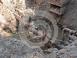 Broken city sewage conduit system after erthquake. deep hole in the ground with cracked pipeline and dirty water pool