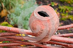 A broken clay pot of brown hanging on a fence of wood