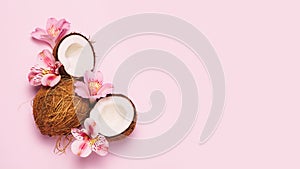 Broken coconut with tropic flowers on pink background photo