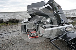 Broken computer parts, monitors and printers in front of nature landscape with a river background. Discarded electronic