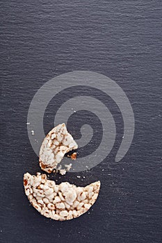 Broken crispbread on stone plate. Dark background. Copyspace for text.