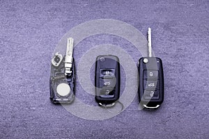 Broken or damaged remote key fob and new vehicle key on gray background. Broken or damaged remote key fob of any vehicle car