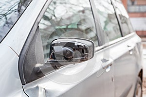 Broken and damaged side mirror on the car doors with remaining wires holding plastic frame without glass