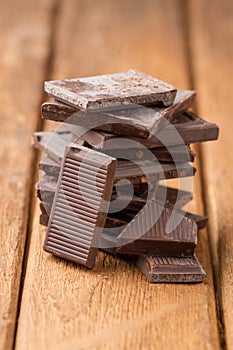 Broken dark chocolate bar on a wooden table
