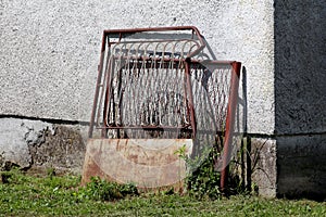 Broken destroyed twisted rusted metal outdoor fence doors with dilapidated white panel left next to family house wall