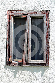 Broken destroyed window with double glass inside dilapidated wooden frame on side of abandoned family house