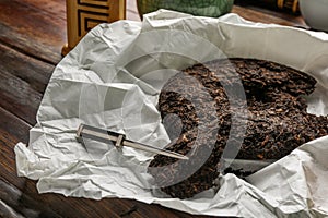 Broken disc shaped pu-erh tea and knife on wooden table