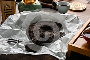 Broken disc shaped pu-erh tea and knife on wooden table