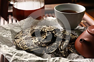 Broken disc shaped pu-erh tea on parchment paper, closeup. Traditional ceremony