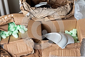 Broken dish in a damaged cardboard box