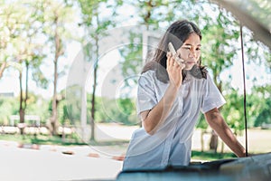 Broken down car concept. Young woman looking at her broken down car