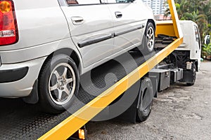 Broken down car towed onto flatbed tow truck with hook cable