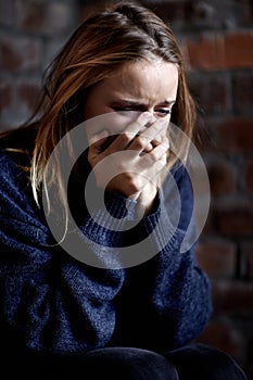 Broken down emotionally. Abused young woman crying hard and covering her mouth.