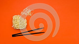 broken dry instant noodles with chopsticks orange background. High quality photo