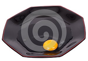 Broken egg on the black plate