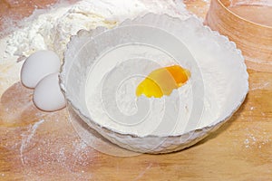 Broken egg in bowl with flour and two whole eggs