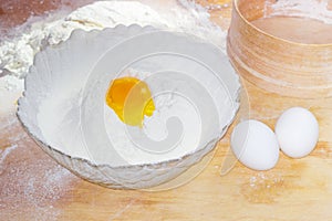 Broken egg in bowl with flour and two whole eggs