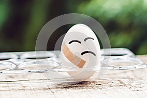 Broken egg with sticking plaster. Concept of brittleness and pain