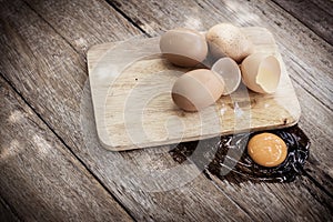 Broken egg on a wooden cutting board on wooden