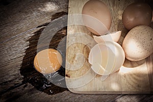 Broken egg on a wooden cutting board on wooden