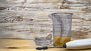 Broken eggs in a blender bowl on a wooden background