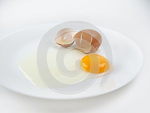 Broken eggs on a plate white background. reddish yellow.