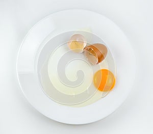 Broken eggs on a plate white background. reddish yellow