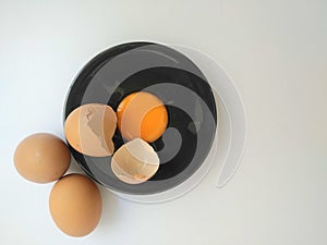 Broken eggs on white wooden table, top view.