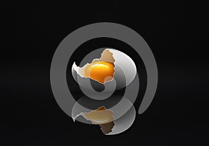 Broken eggshell with raw egg on a black minimalist surface reflective background