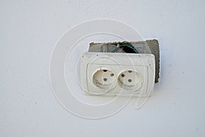 Broken electrical socket on a white wall