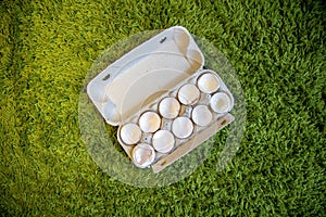 10 broken empty egg shells lie in a box on artificial grass. top view, close-up