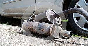 Broken exhaust and muffler of a car, rusted silencer fallen down on the road, breakdown of vehicle