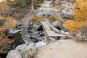 Broken foot bridge over rushing stream and rocks